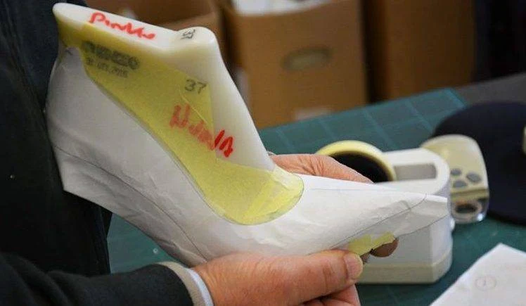 Hands shaping a shoe upper around a last